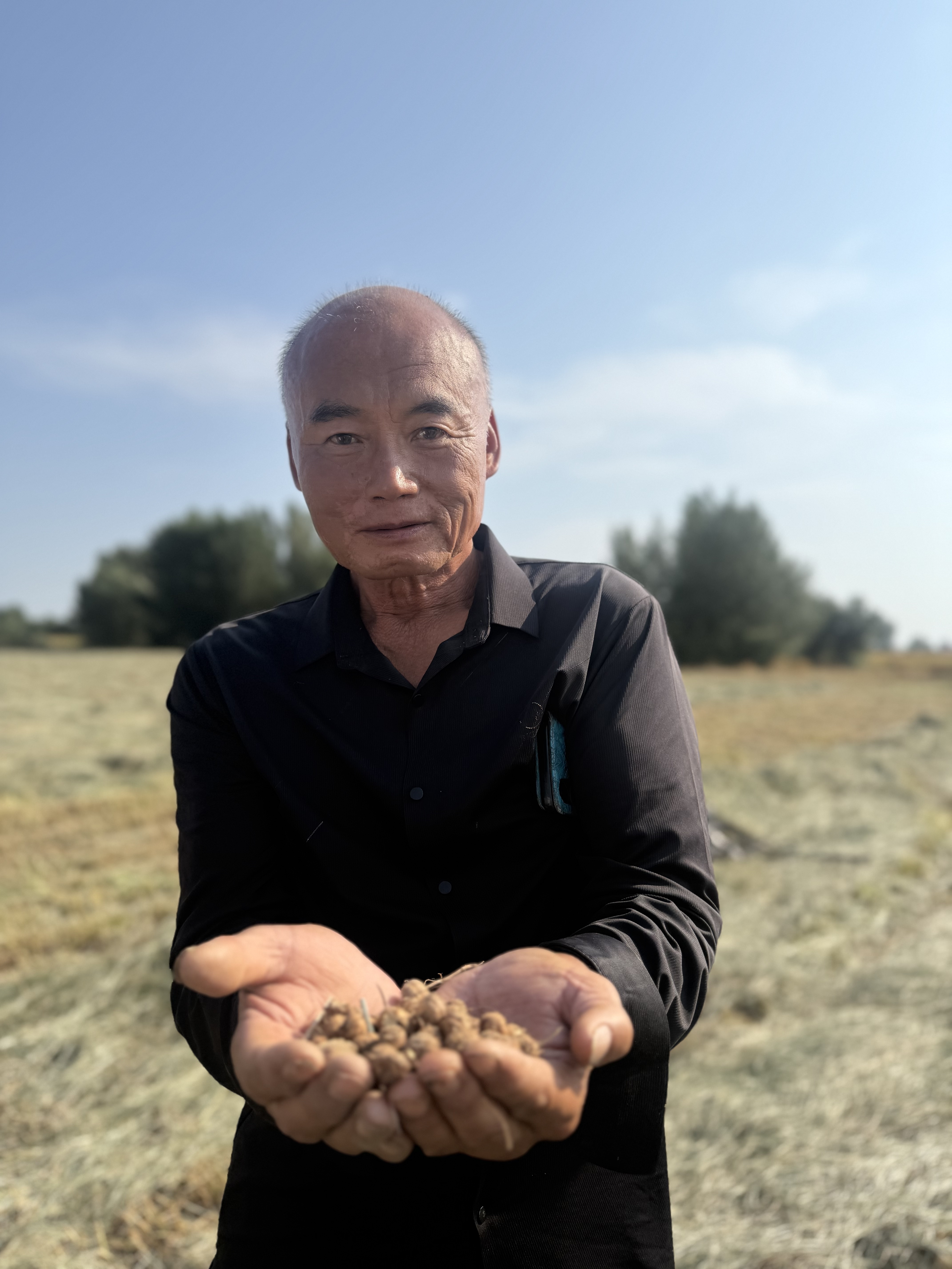 A farmer holding a harvest in a dry field